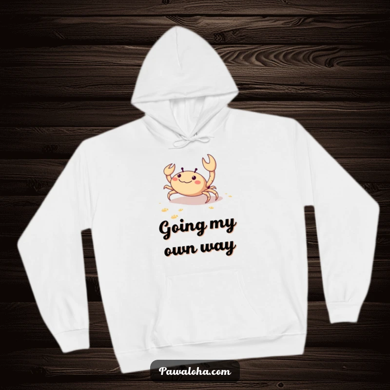 Funny hoodie featuring a delighted crab scuttling sideways on the beach, leaving a trail of tiny footprints, full of seaside glee.